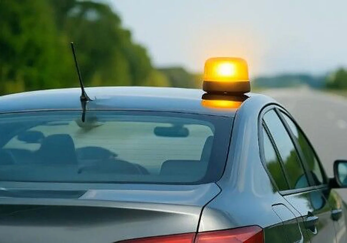 Dispositivo de señalización luminosa V-16 conectado sobre el techo de un vehículo en la carretera.