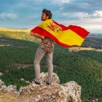 Un hombre en la cima de una montaña durante el amanecer, simbolizando la reflexión sobre la regeneración de España.