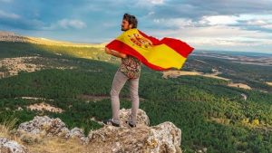 Un hombre en la cima de una montaña durante el amanecer, simbolizando la reflexión sobre la regeneración de España.