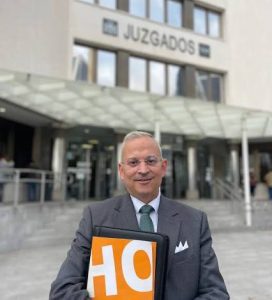 Javier Pérez Roldan con carpeta de HO ante unos juzgados