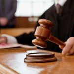Un primer plano del mazo de un juez de madera sobre su base en un tribunal español difuminado