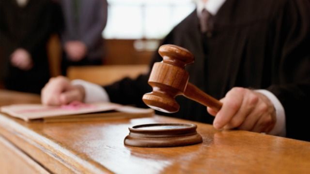 Un primer plano del mazo de un juez de madera sobre su base en un tribunal español difuminado