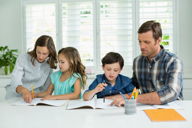 Padres estudiando con sus dos hijos