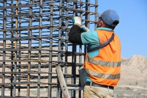 Obreros de la construcción trabajando sobre una estructura de hormigón en una edificación urbana.