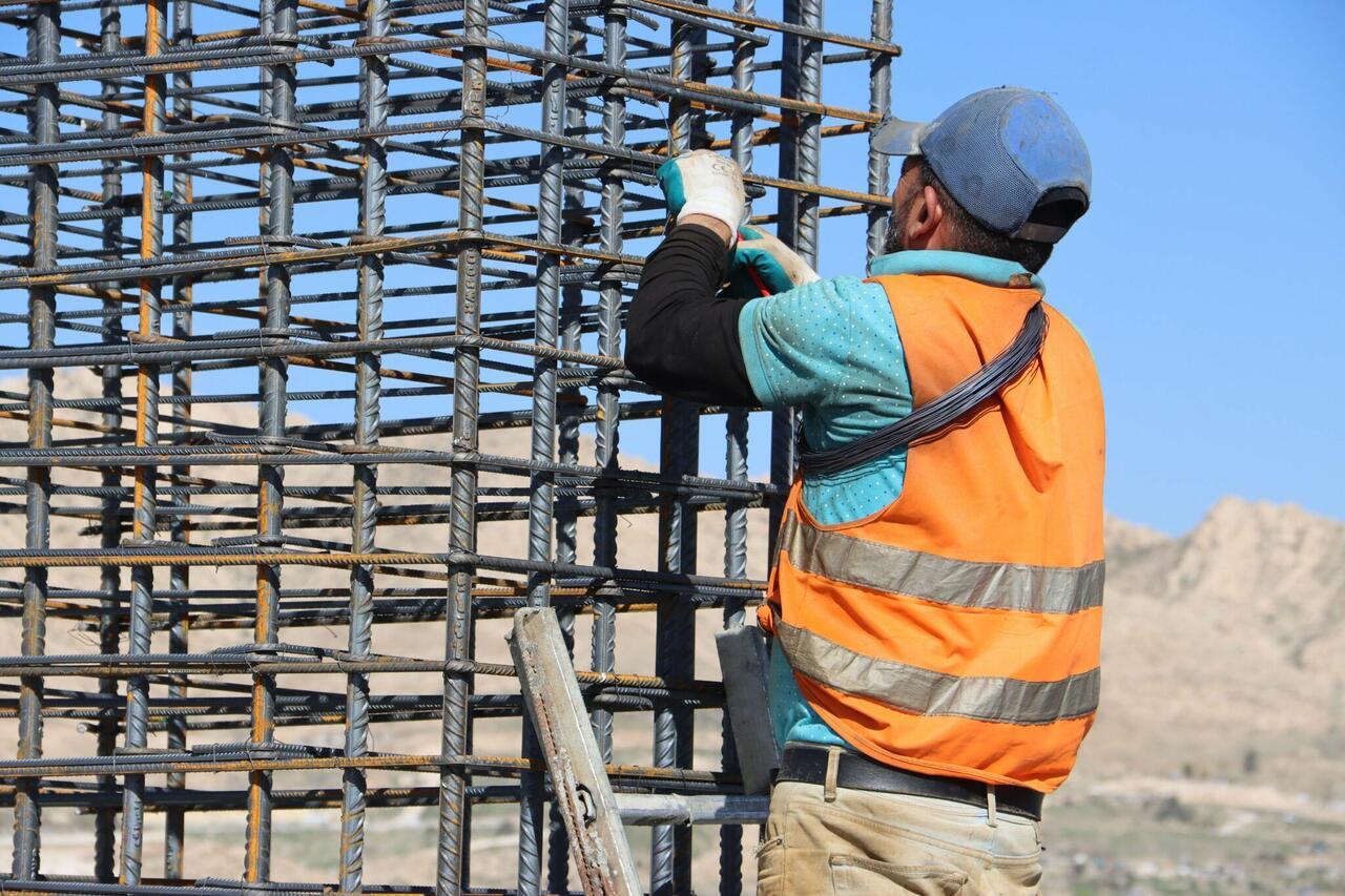 Obreros de la construcción trabajando sobre una estructura de hormigón en una edificación urbana.