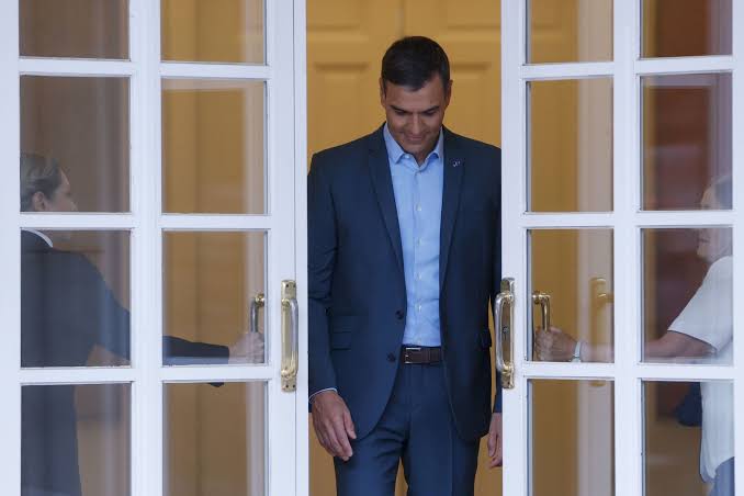 Sánchez saliendo de la moncloa y dos personas le abren las puerats