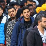 Migrants queue at the arrival centre for asylum seekers at Reinickendorf district in Berlin